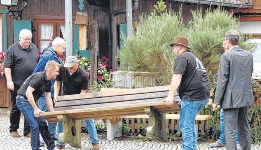 Karl, der Bürgermeister (links), beaufsichtigt seine Vereinskollegen beim Aufstellen der gestifteten Sitzbank. (Foto: Ostermaier)